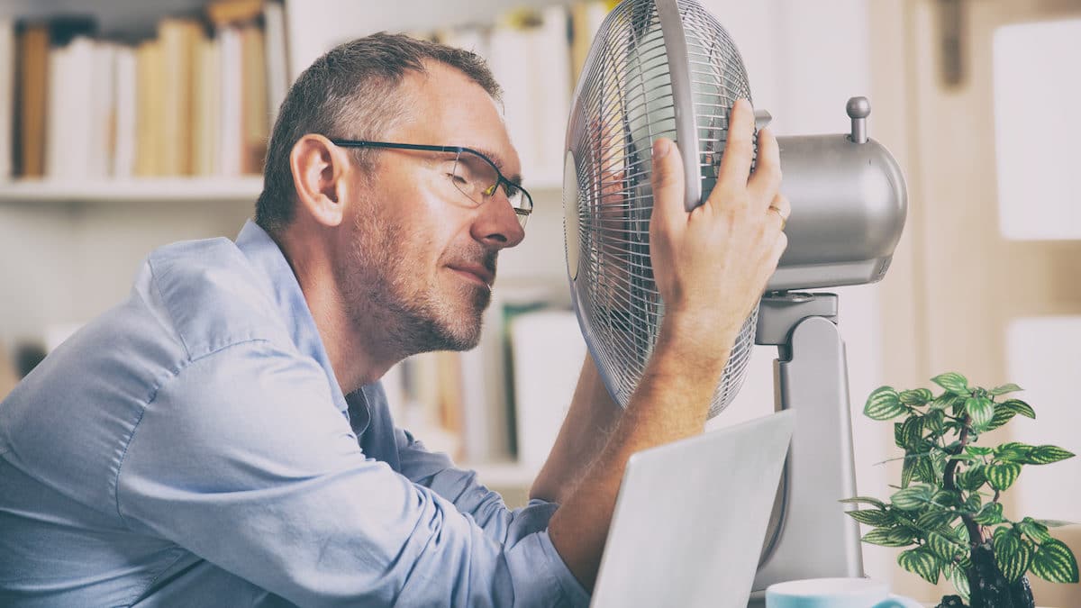 Man in front of a fan needing Summertime AC solutions.