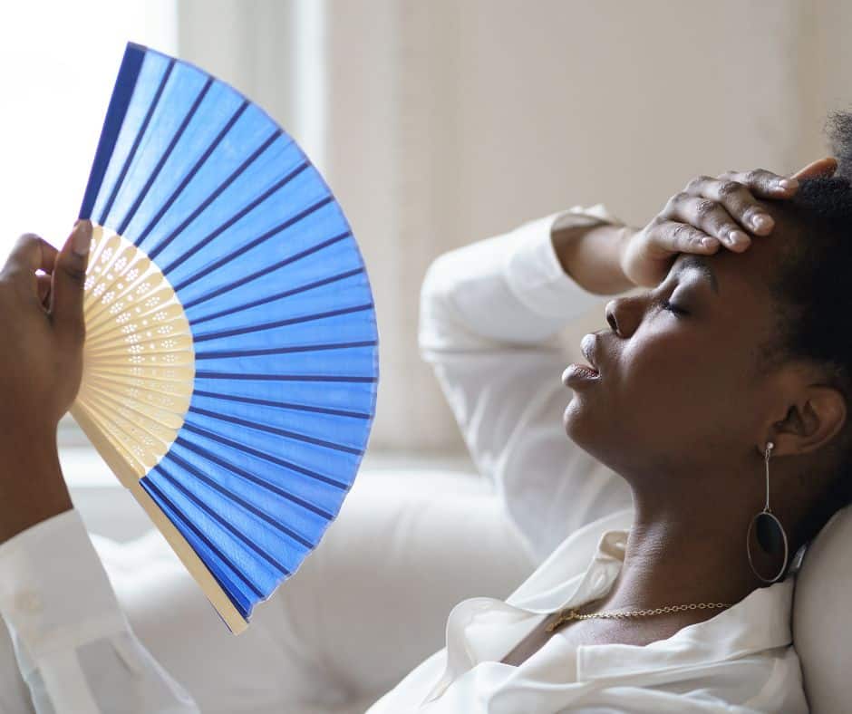 Heat Stroke Vs. Heat Exhaustion_ Woman lying down from the heat with a blue hand fan
